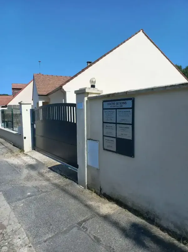 L'entrée côté rue : un portail gris, et la plaque « Centre de soins » sur le mur à sa droite